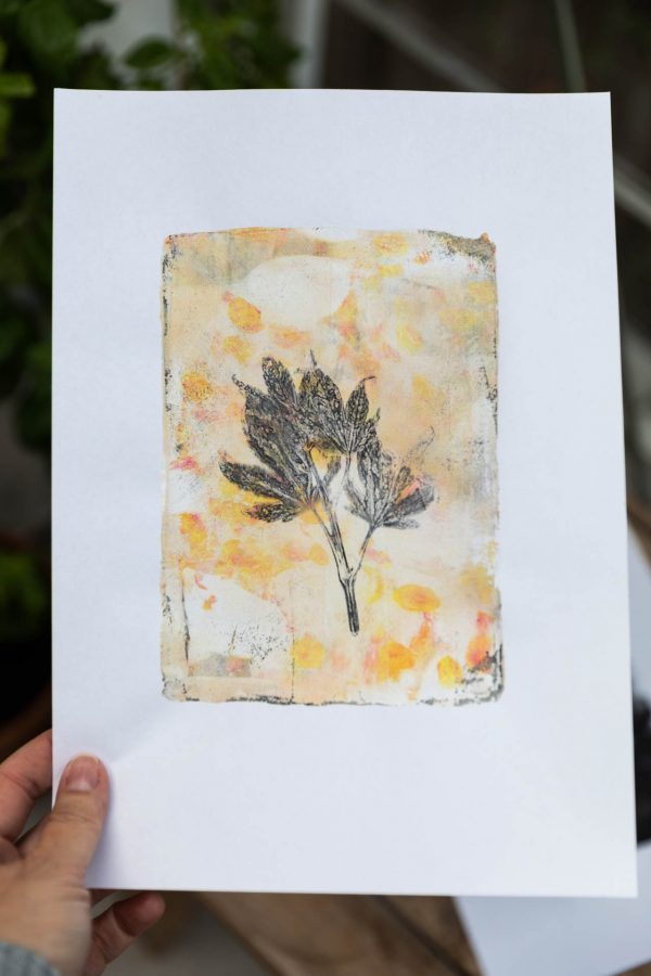 Gel Print mit einem schwarzen Herbstblatt auf Gelb- und Goldtönen auf DIN A 4.