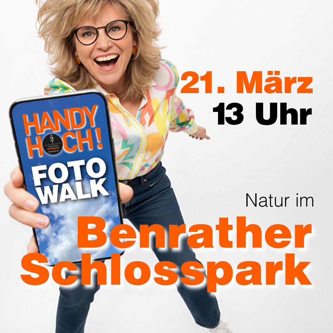 Frau hält iPhone in die Kamera. Auf dem Display steht: HANDY HOCH! Foto Walk Text im Bild: im Benrather Schlosspark. 21. März 2026 um 13 Uhr.