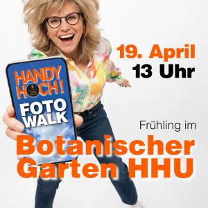 Frau hält iPhone in die Kamera. Auf dem Display steht: HANDY HOCH! Foto Walk Text im Bild: Frühling im Botanischen Garten der HHU 19. April 2026 um 13 Uhr.