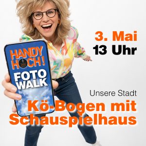 Frau hält iPhone in die Kamera. Auf dem Display steht: HANDY HOCH! Foto Walk Text im Bild: Unsere Stadt am Kö-Bogen und Schauspielhaus 3. Mai 2026 um 13 Uhr.